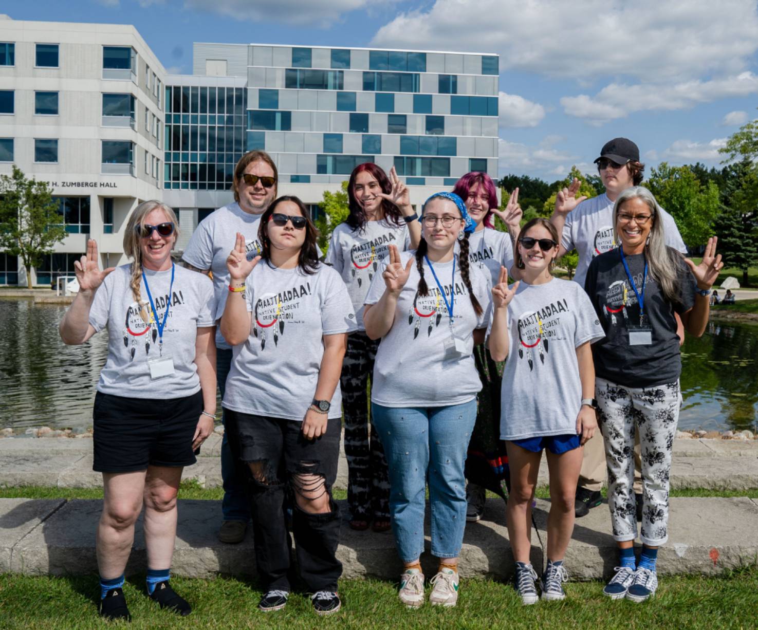 Native American students stand in front of a pond